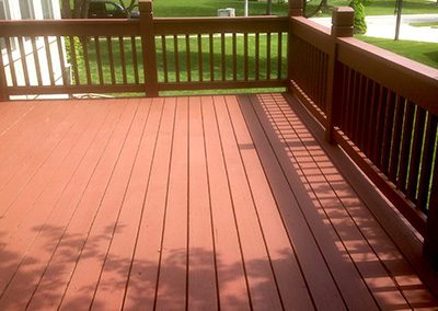 Deck staining project of brown wooden back deck.